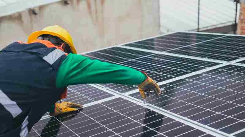 Technician installing solar panels on a rooftop for sustainable energy solutions., tags: renewable plans - pexel